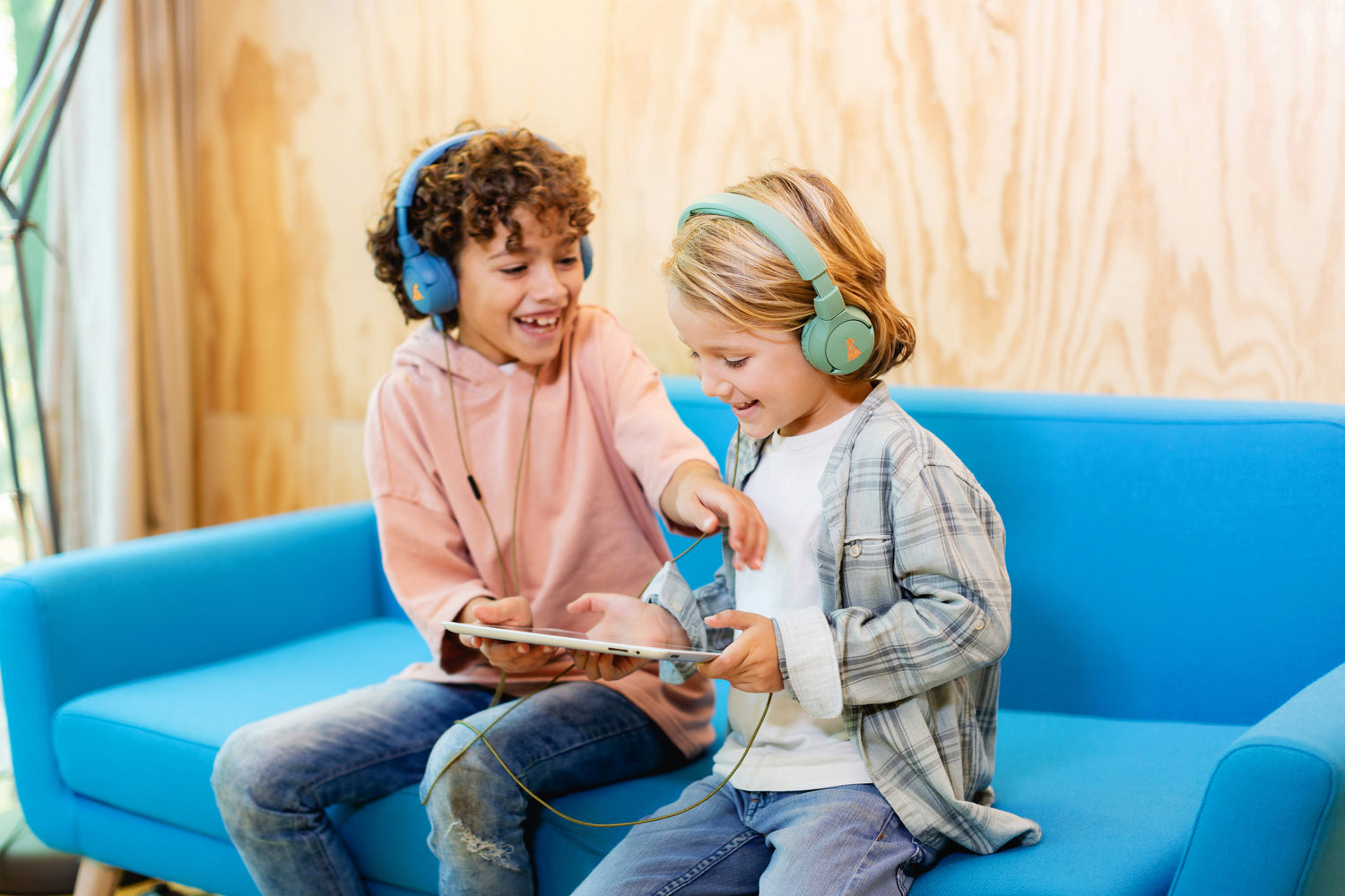 Two boys on a couch listening together wearing The Elephant headphones